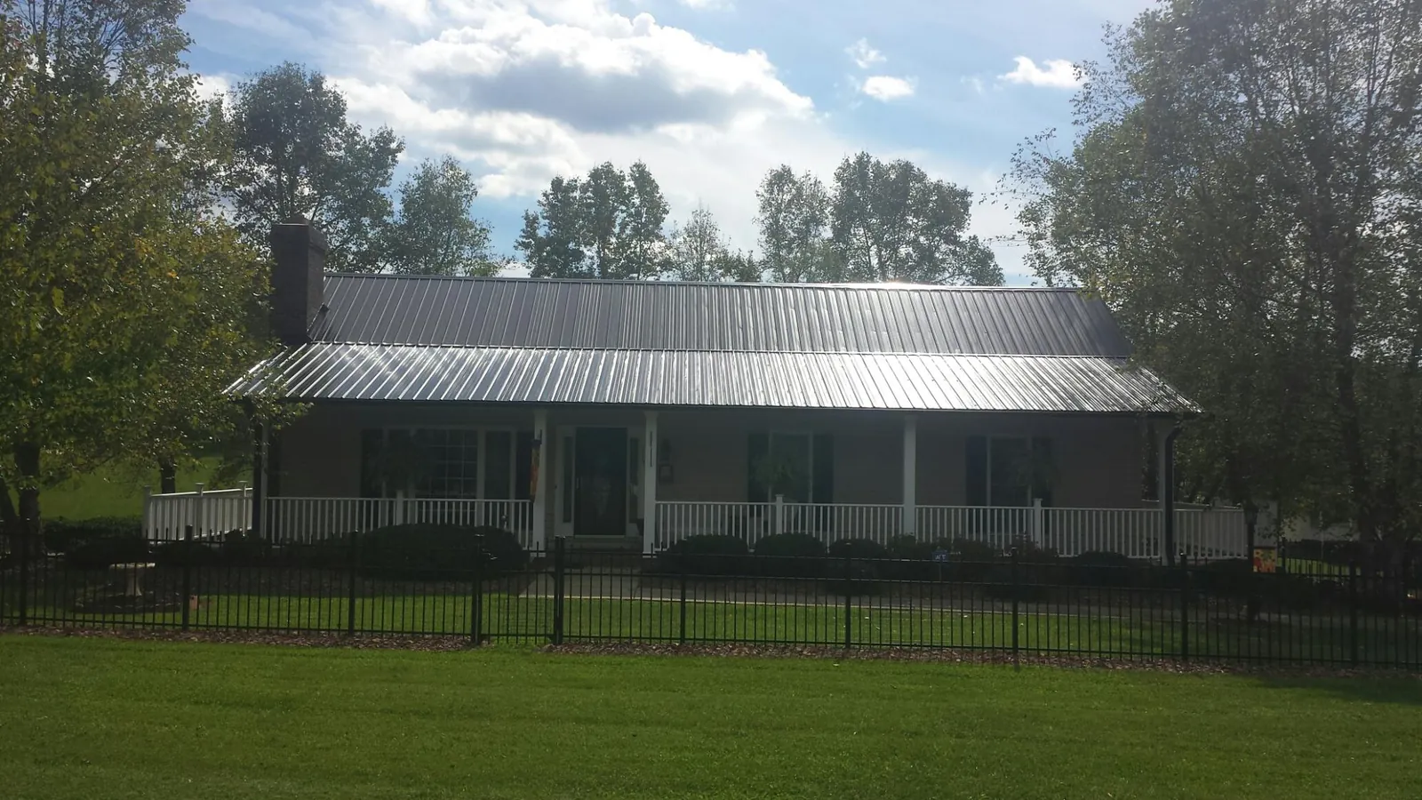 Gray metal roof on a brick ranch with a full width front porch — Gutter Guard Installation work by our crew in Cayce