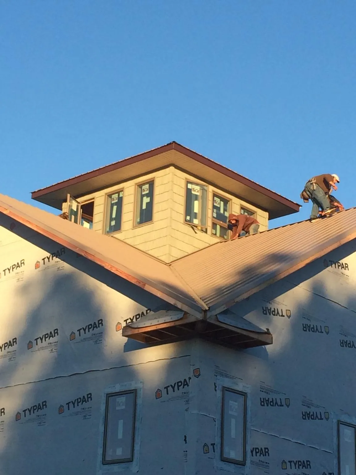 Roofers working around a rooftop cupola on a new metal roof at sunset — Roof Waterproofing in Cayce by Roofing Brothers